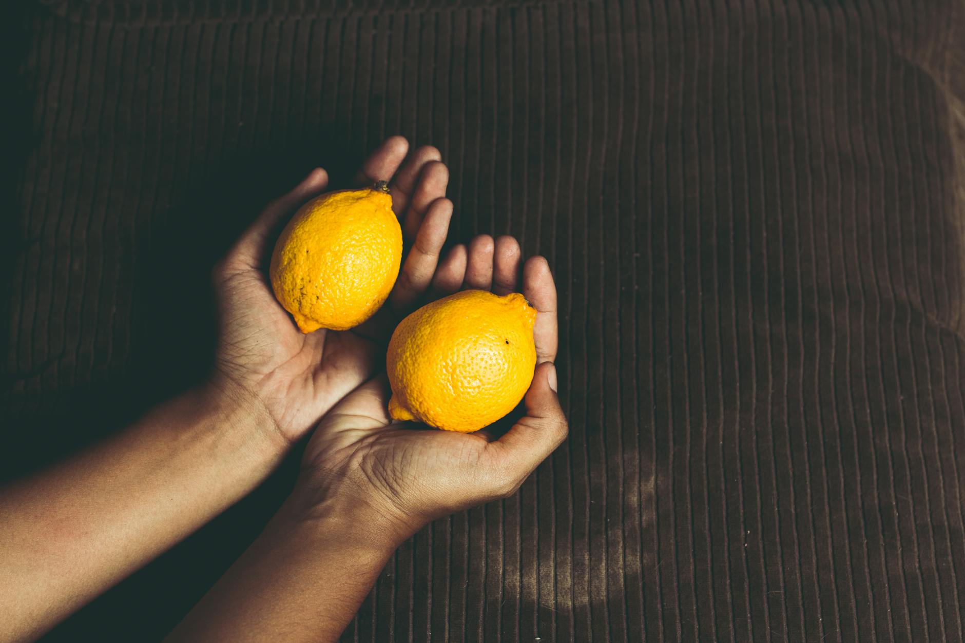 Hand holding a modern orange vibrator against a minimalist purple backdrop, showcasing sensual wellness tools