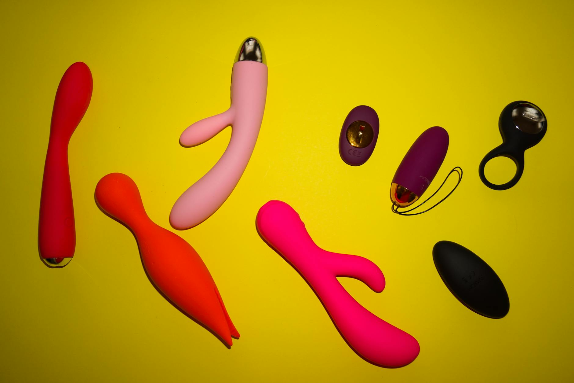 Hands holding colorful silicone vibrators and personal massagers against a soft background
