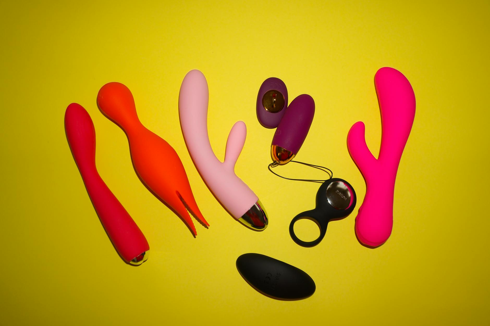 Colorful clitoral vibrators and adult toys displayed on a bright yellow background